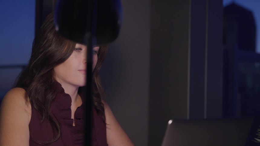 A woman is working on a computer at night