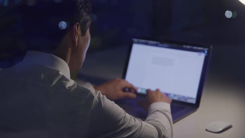 A man on his laptop in his office at night working