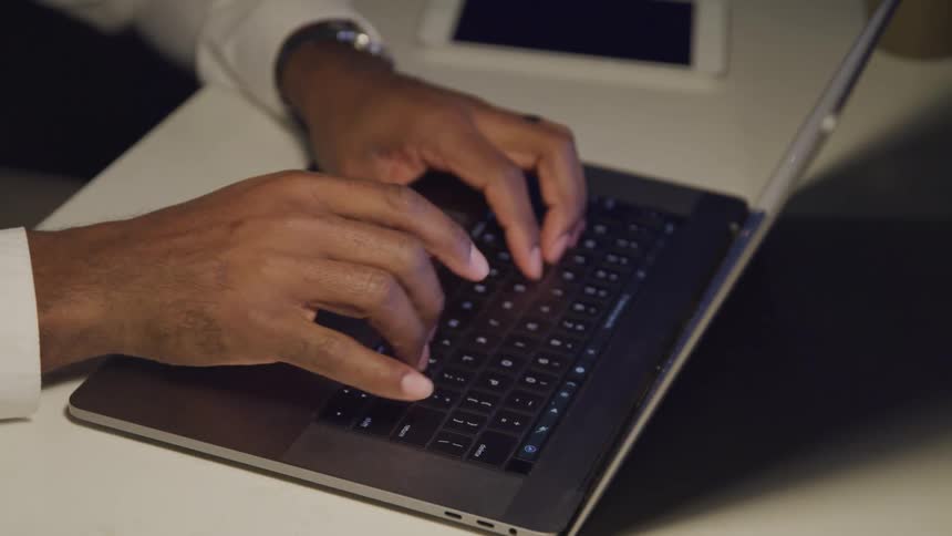 A man is typing on a laptop indoors