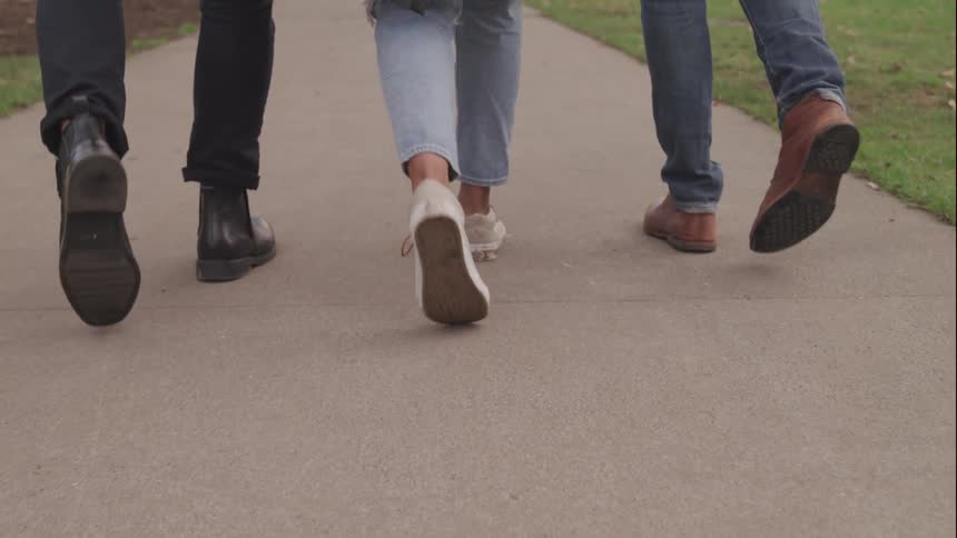 Three people walk down the sidewalk together
