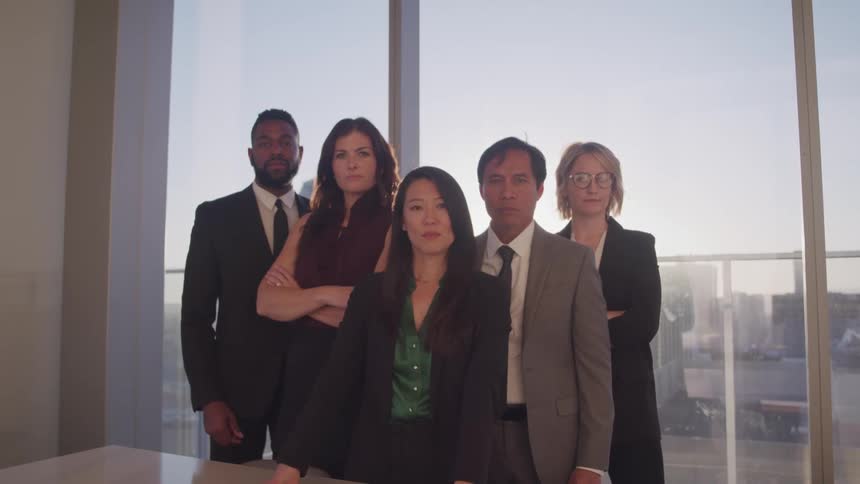 Two men and three women standing behind a table with a window in the background