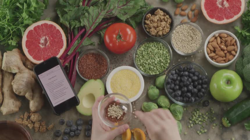 A person preparing a recipe mixing ingredients from a table of food
