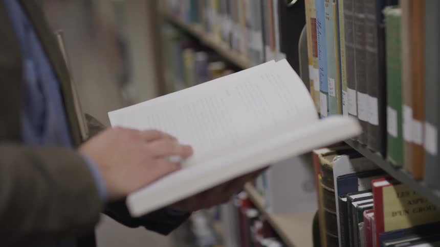 Teenage boy leafs through a book in the public library