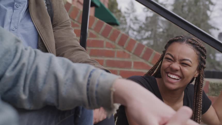 A black female laughing sitting next to two males