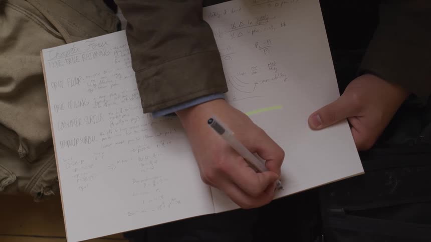 A person handwriting on a notebook using a pen