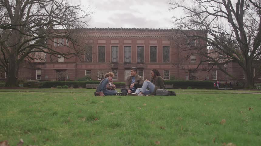 Three friends sitting on the campus lawn talking