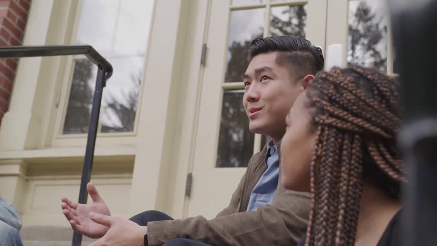 Two friends are talking while sitting outside of a building