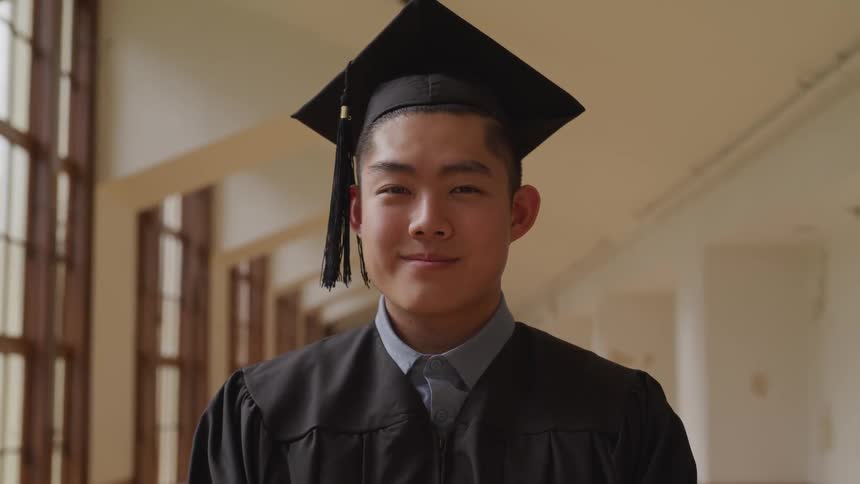 A student smiles in a cap and gown