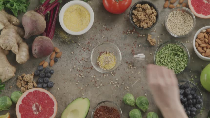 A person scoops multiple herbs and seasonings and places them in another bowl