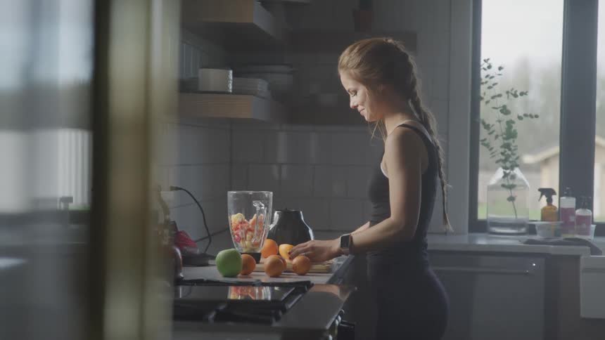 A woman is cutting oranges in her kitchen