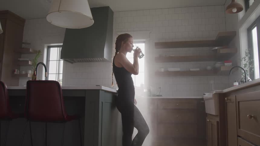 A woman at home drinking a glass of water