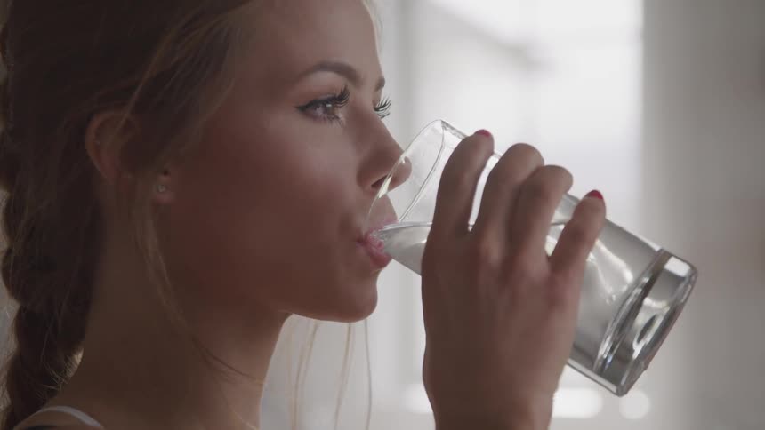 A woman is drinking water indoors