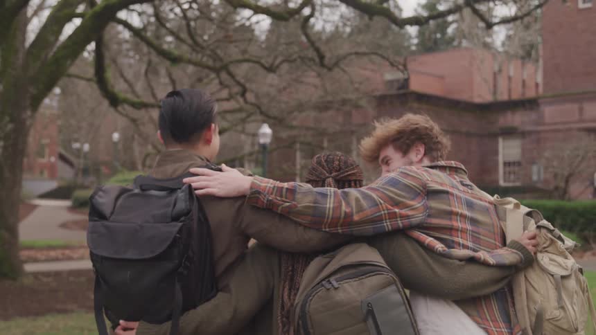 Three students hug as they walk on campus together