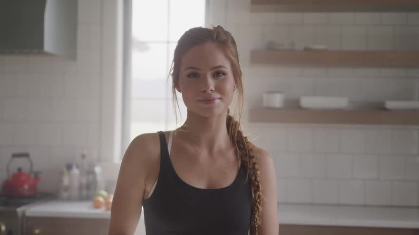 A woman is standing in a house and smiling