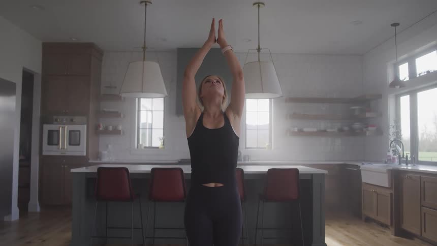 A woman is stretching in a kitchen
