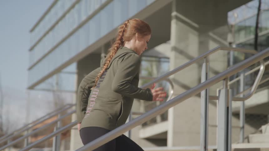 A woman is exercising up a staircase outdoors