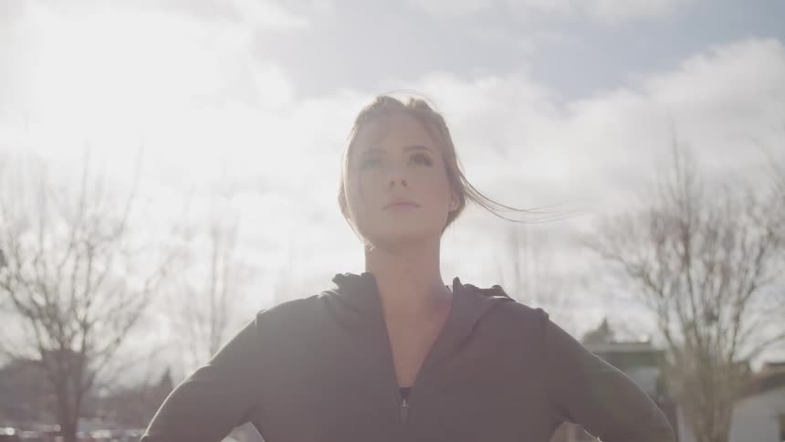 Woman stands outdoors near apartment buildings with hands on hips