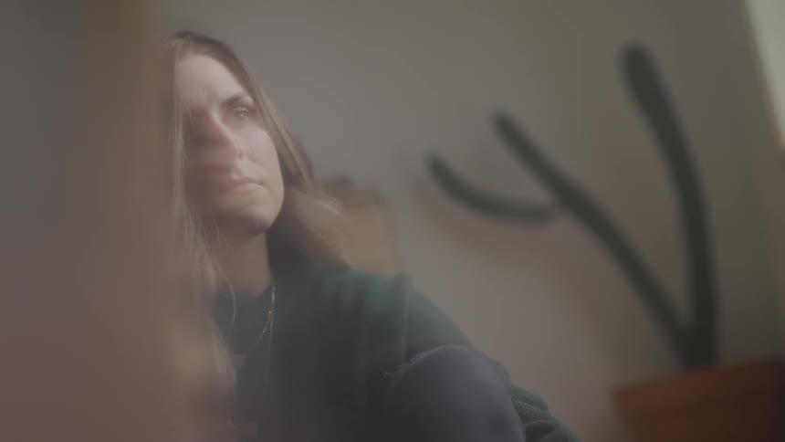 A woman sitting on the floor at home looks up