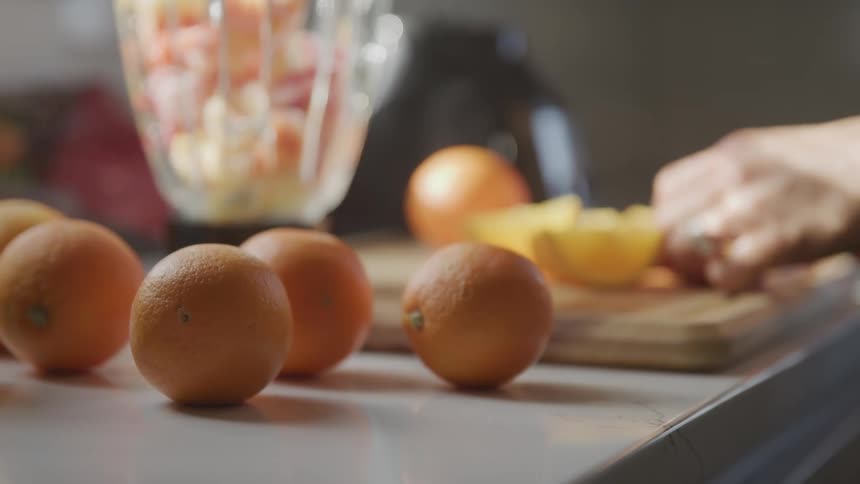 A woman cuts fruit at home to put in a blender