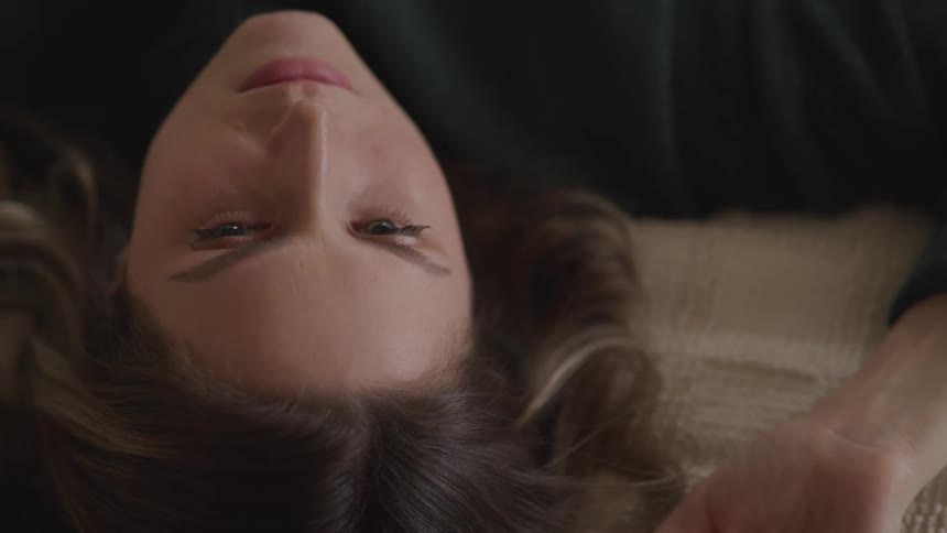 A woman wakes from a rest laying down