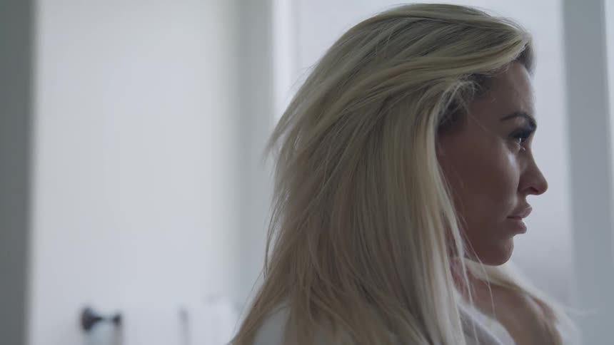 Blonde woman dries her hairwhile wearing robe