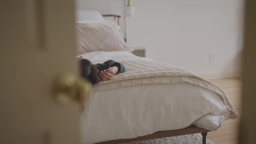 A woman lays on her bed during the daytime