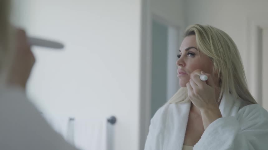 A woman at home puts make up on