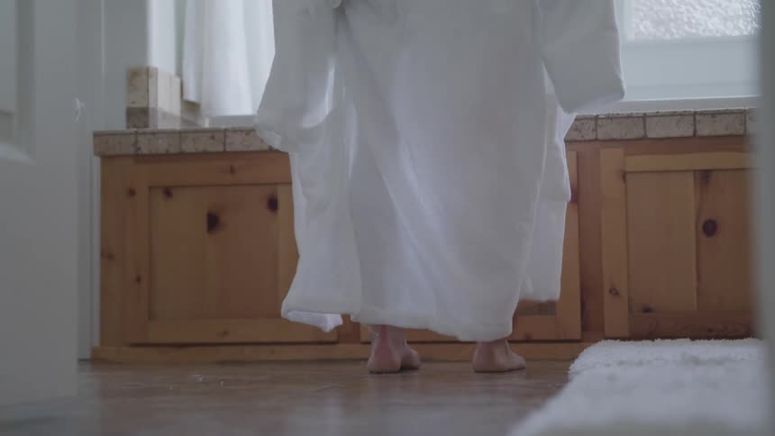 Man takes his white robe out while standing on the bathroom at home