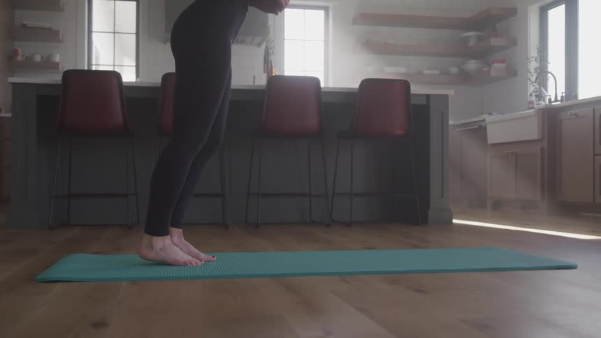 Woman wearing sports outfit practices yoga in the kitchen at home