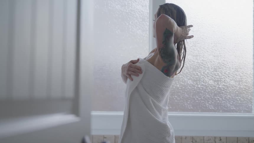 A woman places a towel around her body after getting out of the shower