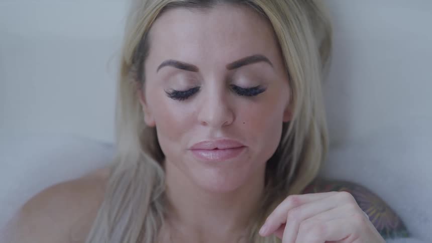 A blonde woman closes her eyes to show her eye makeup and long false lashes