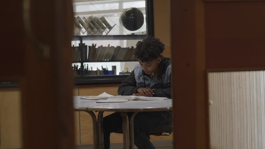 A black male sitting at a table reading a book