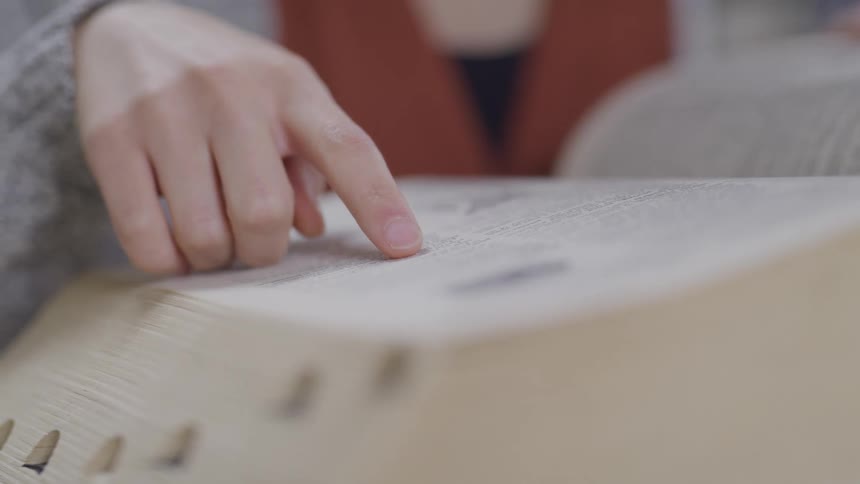 A woman runs her hand along the page of an encyclopedia