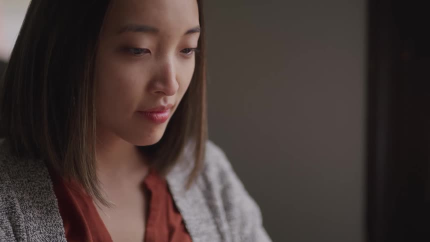 A young asian woman sits indoors during the day
