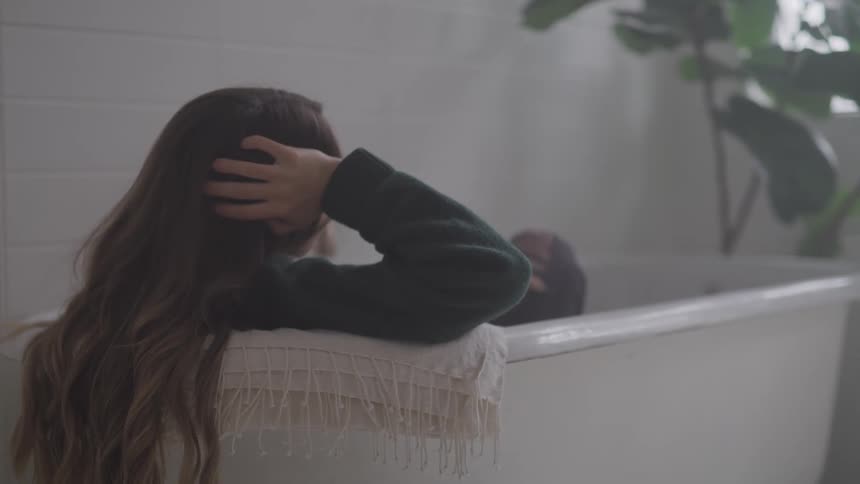 A fully clothed woman sits in a bathtub