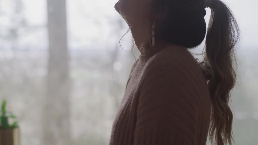 Woman wearing a sweater stands on a room at home relaxing