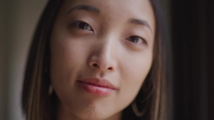 Close up of an asian woman with straight hair and makeup facing the camera with eye contact