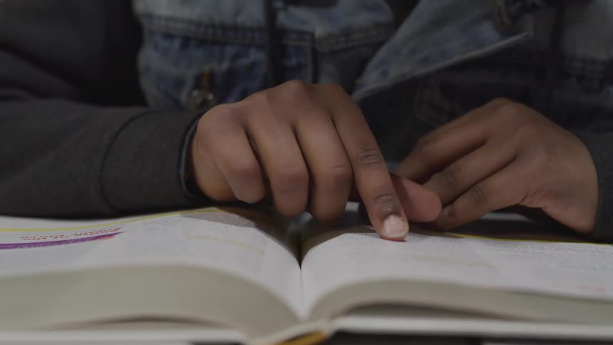 A child follows lines of print as she reads a book