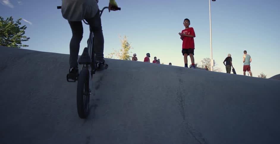 A boy rides a bicycle in a skate park