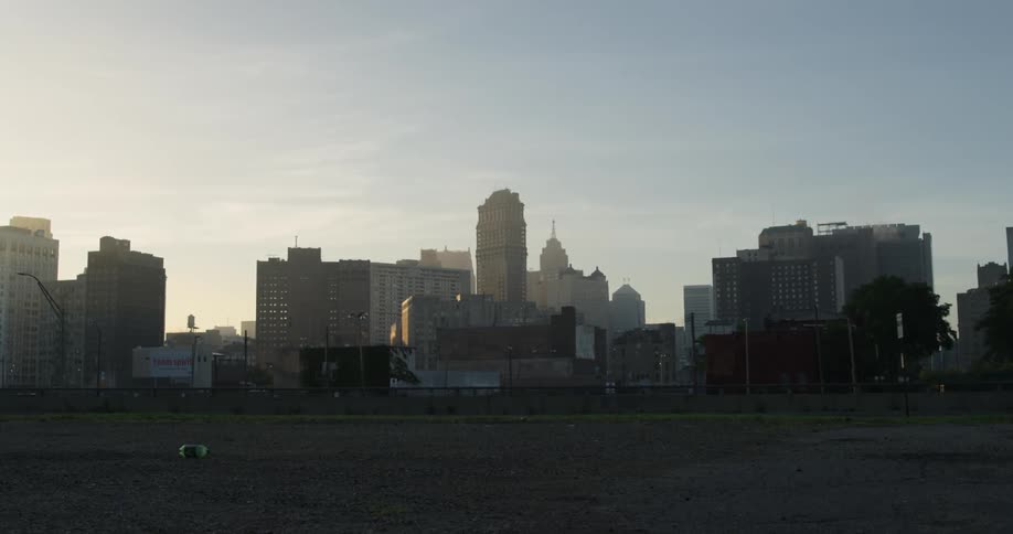 A vehicle drives past a large city in the distance