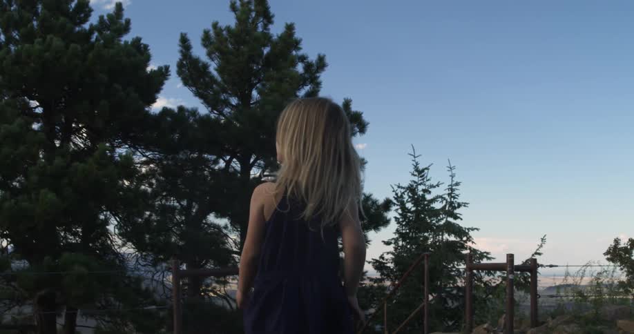 A young girl in a dress is wandering in a forested area