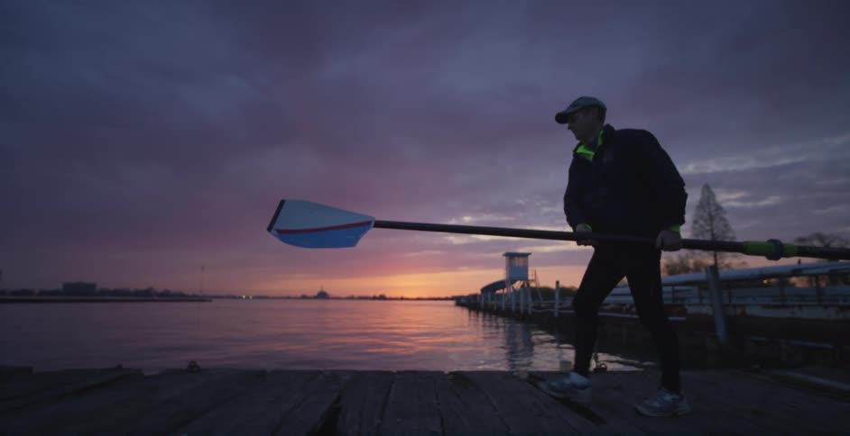 A man holding a long pole walks on a dock
