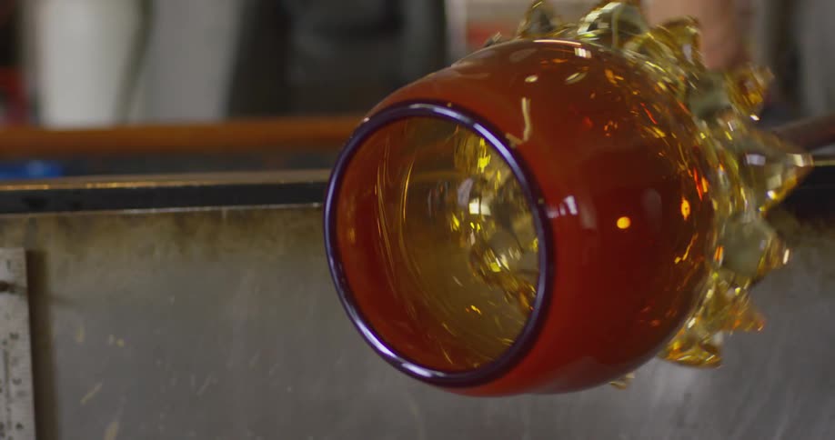 A man is spinning glass into a vase