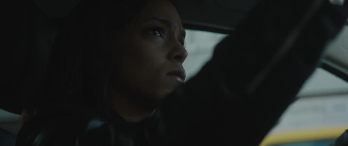 A woman is driving past buildings looking around