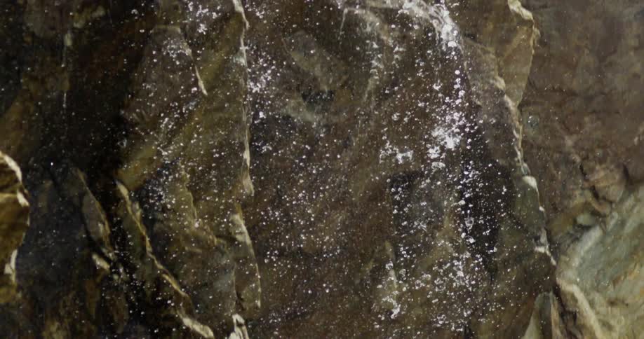 Water falls against rocks in slow motion