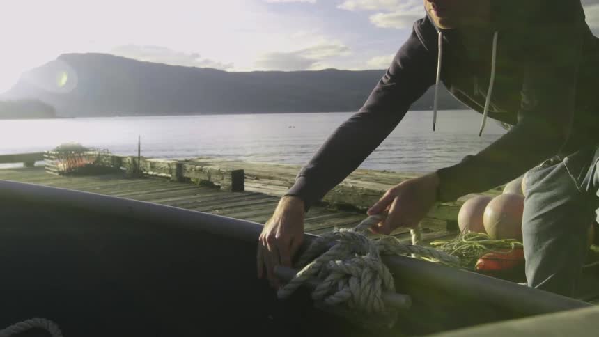 A man tying off a boat to a dock