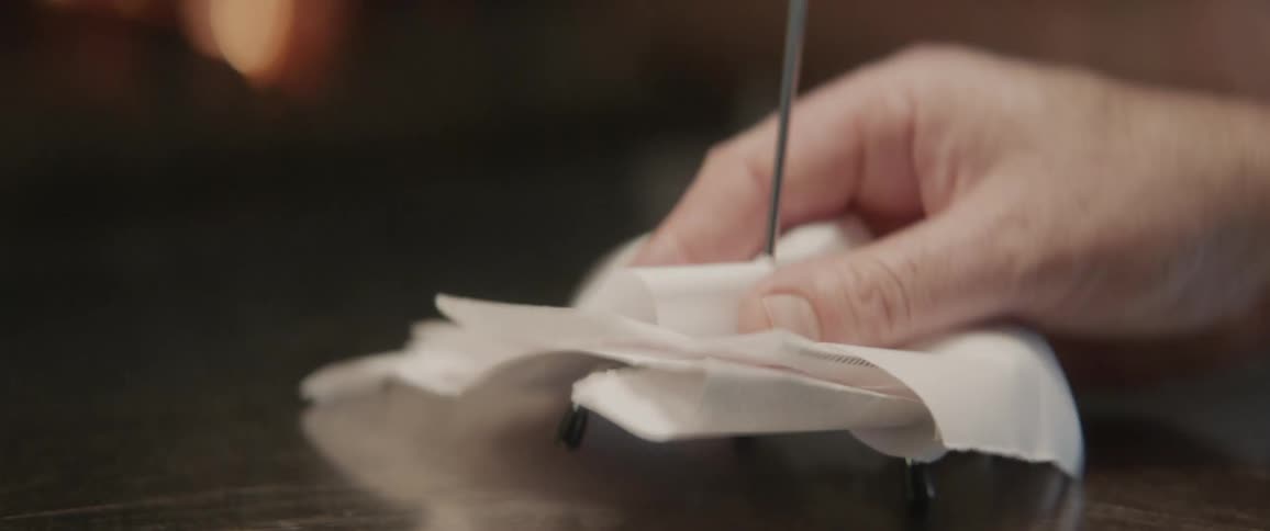 Person puts a piece of paper on a needle on a stack of papers