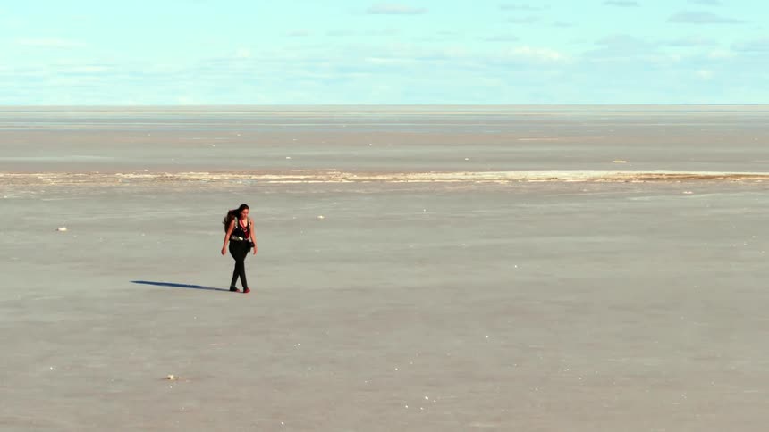 Aerial of a woman walking across a vast desert
