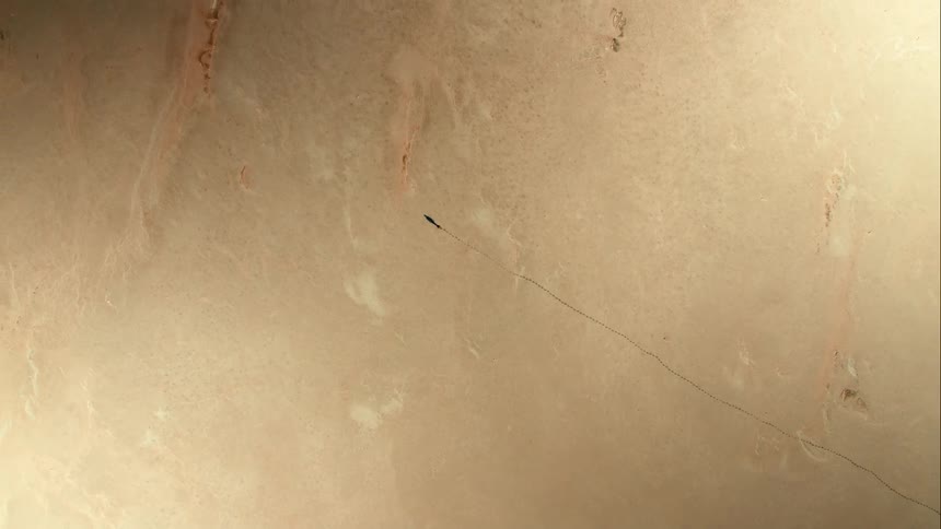 Aerial rise above a person walking through endless brown desert