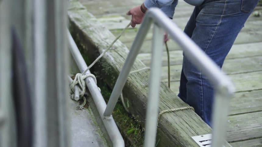 A man unties a boat from a dock